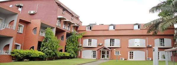 A multi-story building with a brick facade, multiple balconies, and a central entrance.