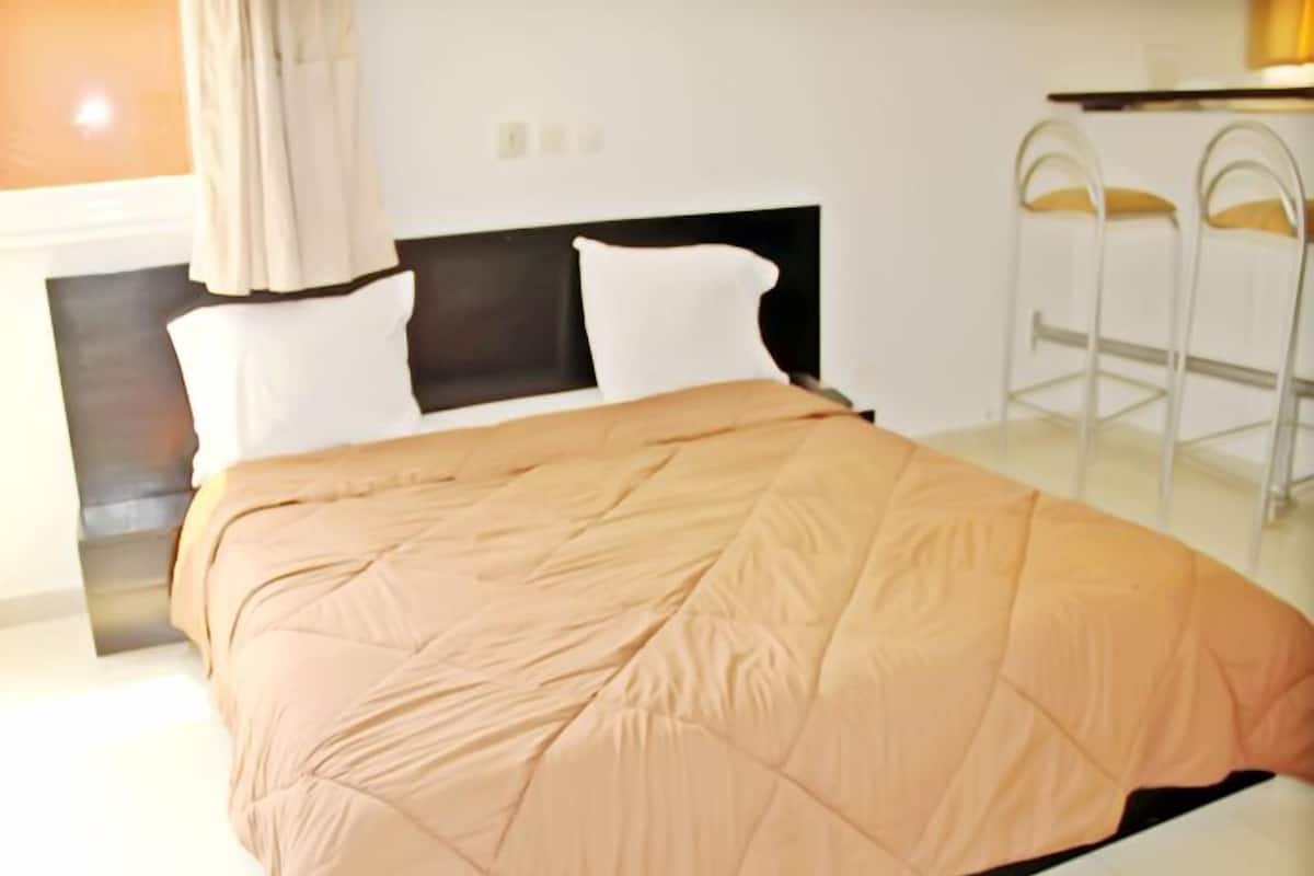 A neatly made bed with a beige duvet, a black headboard, and two white pillows.