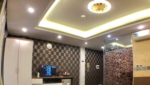 A modern hotel room with a bed, a desk with a computer, a wardrobe, and a shower area. - The Royal Hotel (Hanoi)