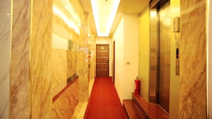 A hotel corridor with marble walls, a red carpet, and two elevators. - The Royal Hotel (Hanoi)