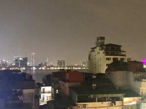 A nighttime cityscape with buildings and a river. - The Royal Hotel (Hanoi)
