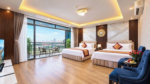 A hotel room with two beds, a TV, a balcony with a city view, and a dining area.