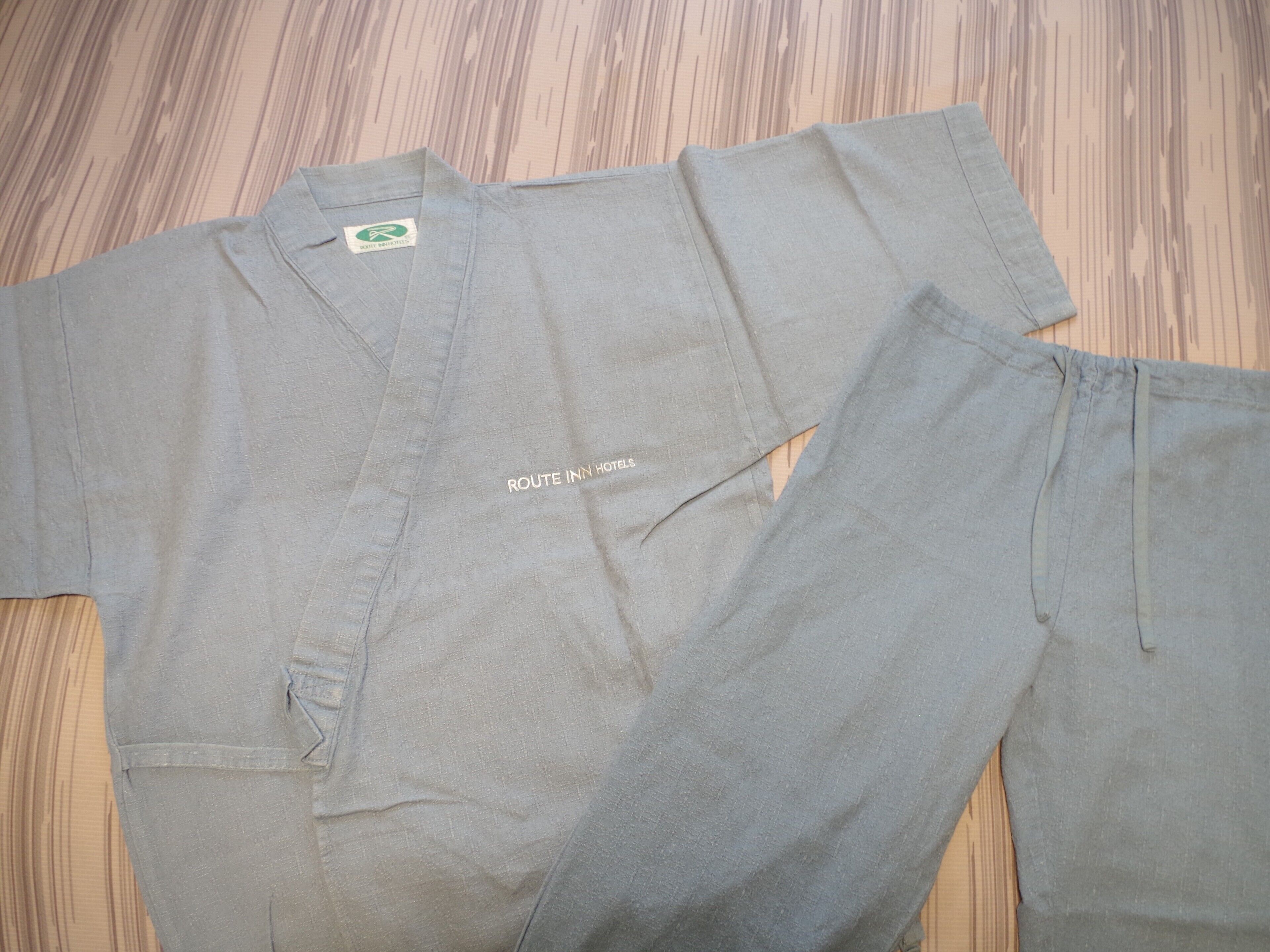A grey shirt and pants laid out on a wooden floor.