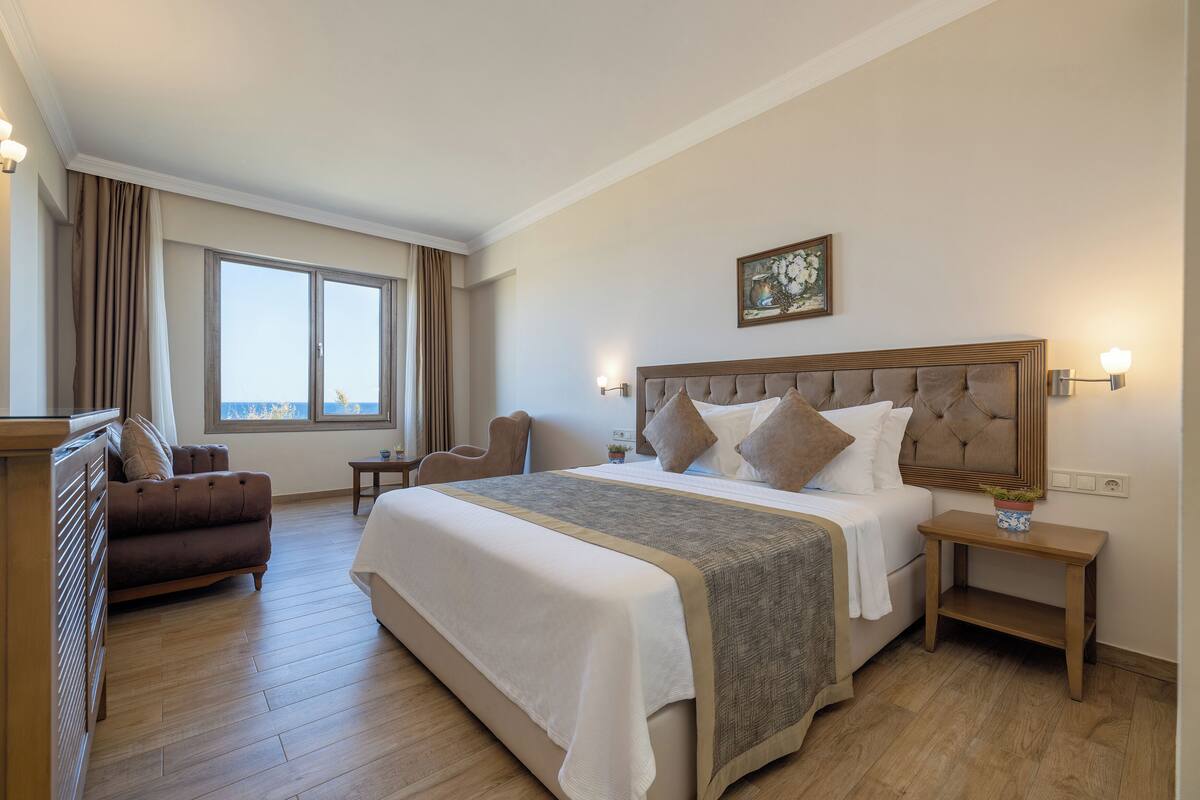 A hotel room with a large bed, a sofa, a desk, and a window with curtains.