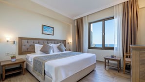 Habitación de hotel con una cama grande, mesitas de noche, vista al mar y un cuadro en la pared.