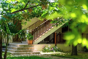 A staircase leading to a building with a wooden railing, surrounded by greenery and potted plants. - Cinarli Kasri Hotel (Gökçeada)