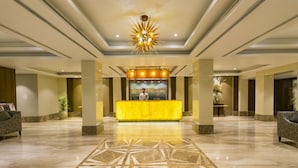 A hotel lobby with a marble floor, a reception desk, and a large chandelier. - The India Benares (Varanasi)