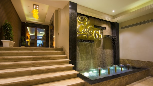 A hotel entrance with a grand staircase, a decorative wall with the hotel's name, and a water feature. - The India Benares (Varanasi)