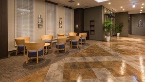 A hotel lobby with a seating area, large windows with blinds, a reception desk, and a potted plant. - Hotel Route-Inn Grand Kitami Ekimae (Kitami)