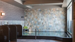 A modern bathroom with a stone wall, a glass partition, and a plant. - Hotel Route-Inn Grand Kitami Ekimae (Kitami)