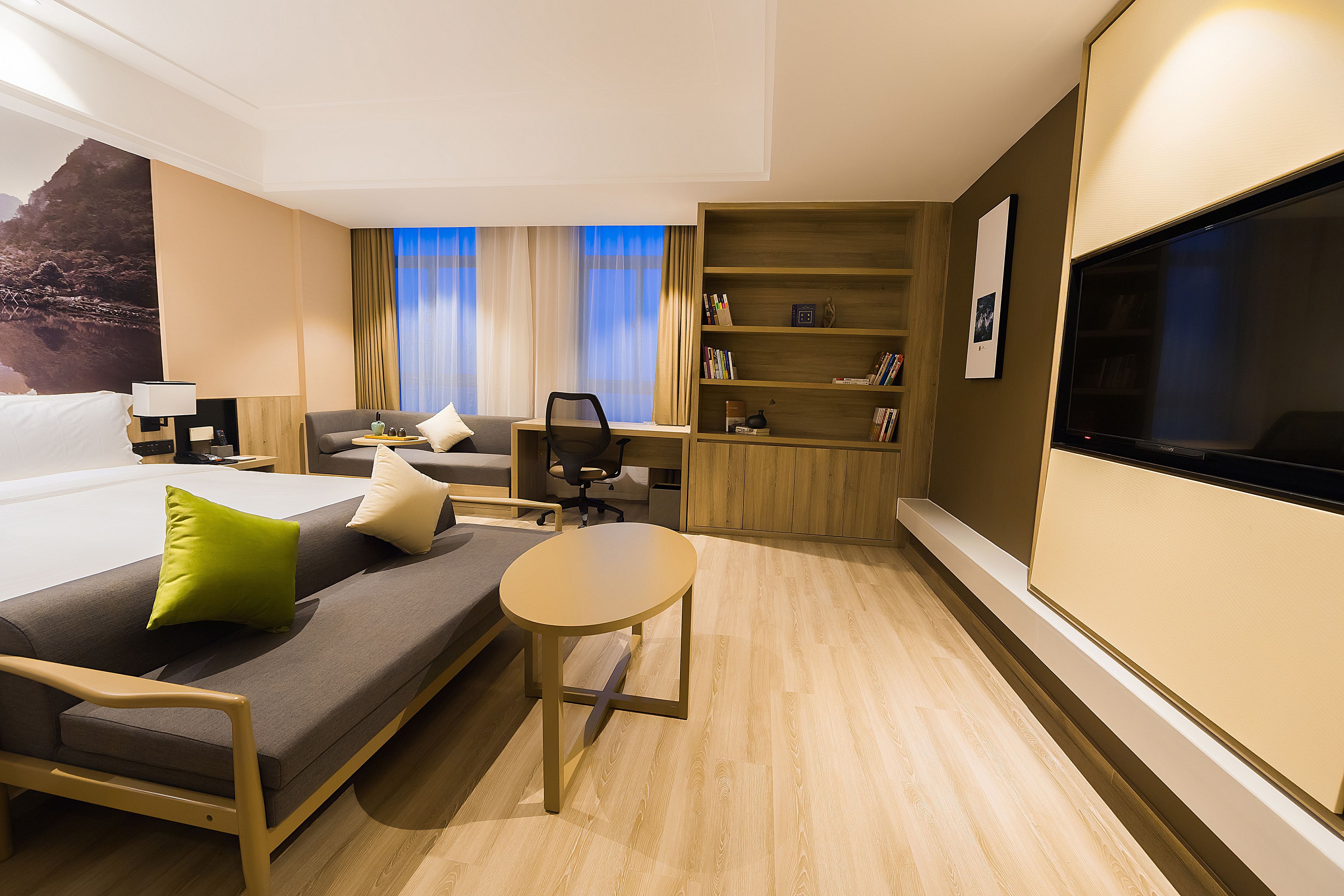 Une chambre d’hôtel comprenant un lit, un canapé, un bureau, une chaise, une petite table, une bibliothèque et un téléviseur.