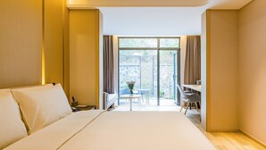 Habitación de hotel con una cama grande, un escritorio y vistas al exterior a través de una puerta corrediza de vidrio.