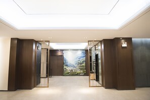 A modern hotel lobby with a skylight, wooden paneling, and a large mural of a mountainous landscape. - Hilton Garden Inn Zhuji East (Shaoxing)