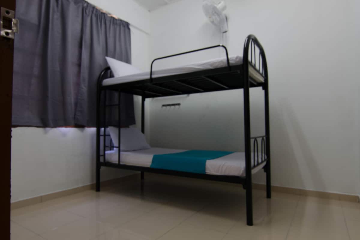 A bunk bed in a room with a window, a curtain, and a wall-mounted fan.
