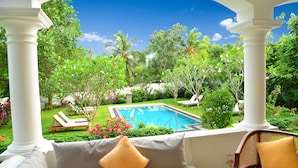 A poolside area with white columns, a pool, and lush greenery. - Boutique Villa Shanthi (Hikkaduwa)