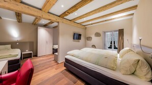 A bedroom with a large bed, a desk, a chair, and a wardrobe.