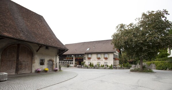 A traditional building with a cobblestone courtyard, wooden doors, and flower boxes on the windows.