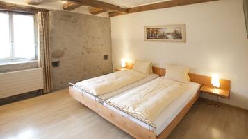 Een slaapkamer met een houten bed, twee nachtkastjes met lampen, een schilderij aan de muur en een raam met gordijnen.