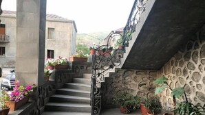 A stone staircase with a wrought iron railing leading to a balcony, surrounded by potted plants and flowers. - Christy Hotel (Goris)