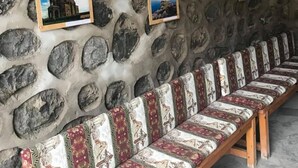 A stone wall with framed pictures and a row of patterned benches. - Christy Hotel (Goris)