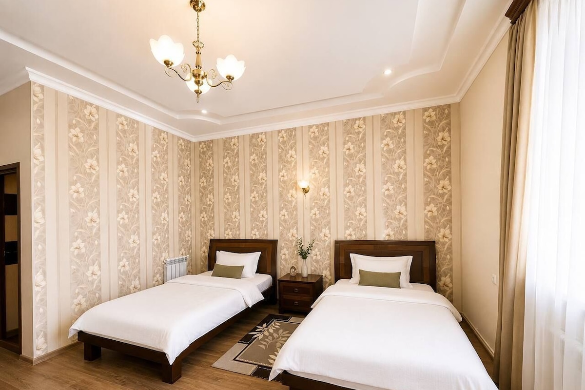 Een hotelkamer met twee bedden, een kroonluchter en bloemenbehang.