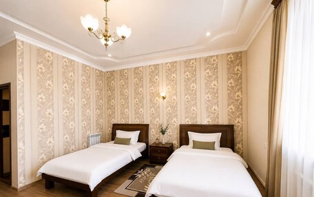 A hotel room with two beds, a chandelier, and floral wallpaper.