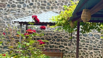 Un muro de piedra con una pérgola de madera y un banco.