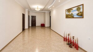A spacious hallway with a polished floor, a chandelier, and a painting on the wall. - Christy Hotel (Goris)
