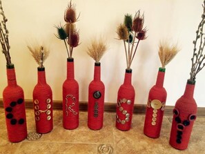 Seven red vases with buttons and decorative elements, each containing dried plants. - Christy Hotel (Goris)
