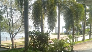 A covered outdoor area with a patterned tile floor, potted plants, and a view of a body of water. - Villa Hotel (Trincomalee)