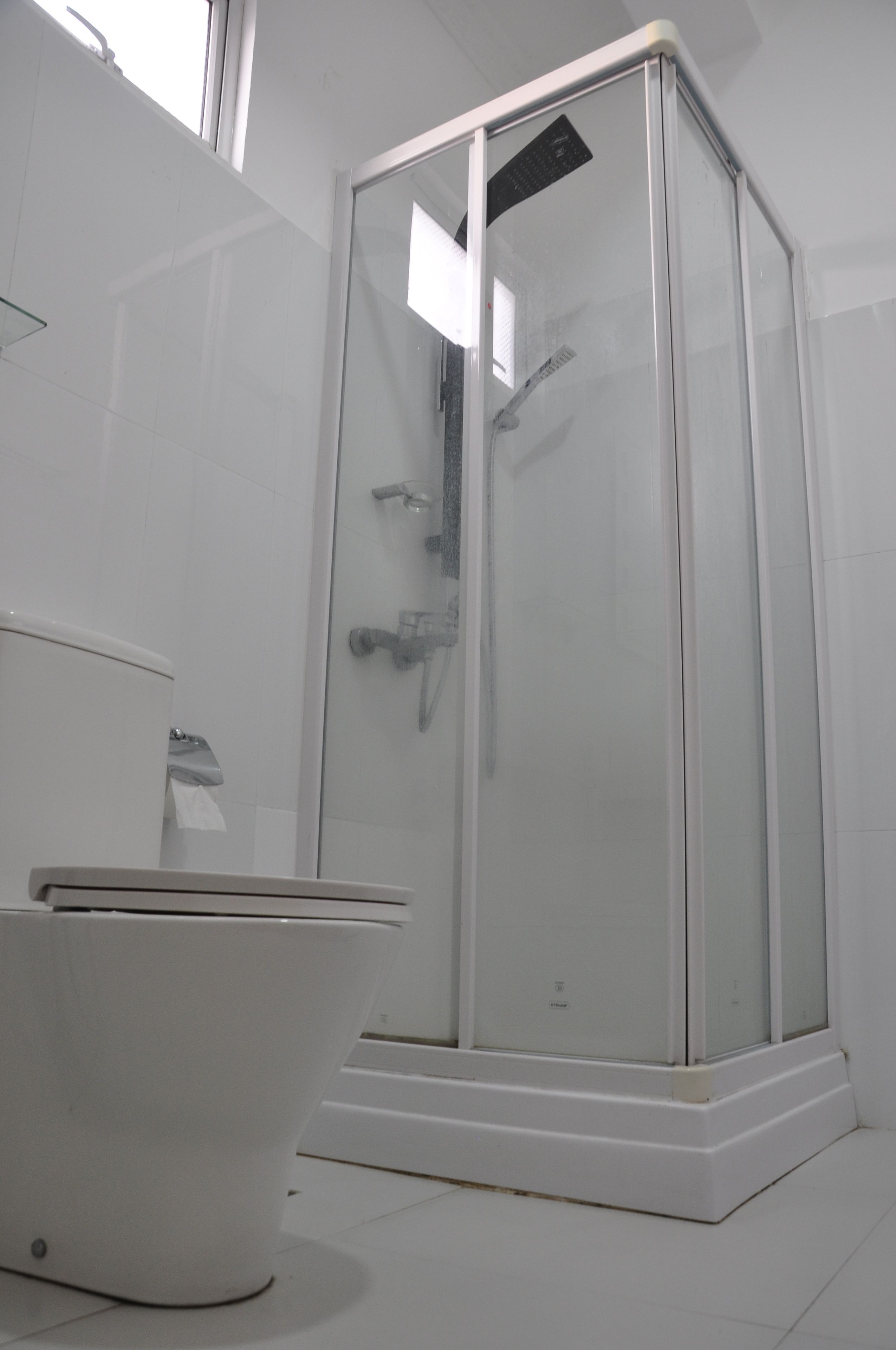 Une salle de bain avec une douche à parois de verre, des toilettes blanches et un lavabo blanc.