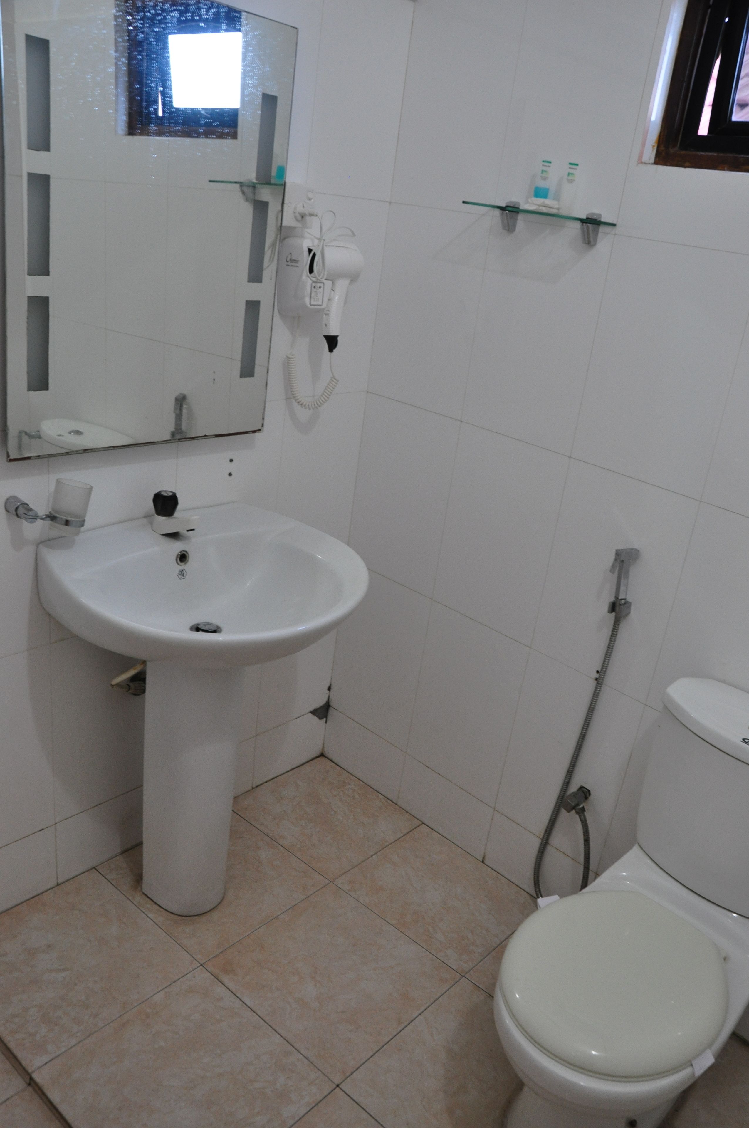 A bathroom with a white sink, mirror, and toilet.