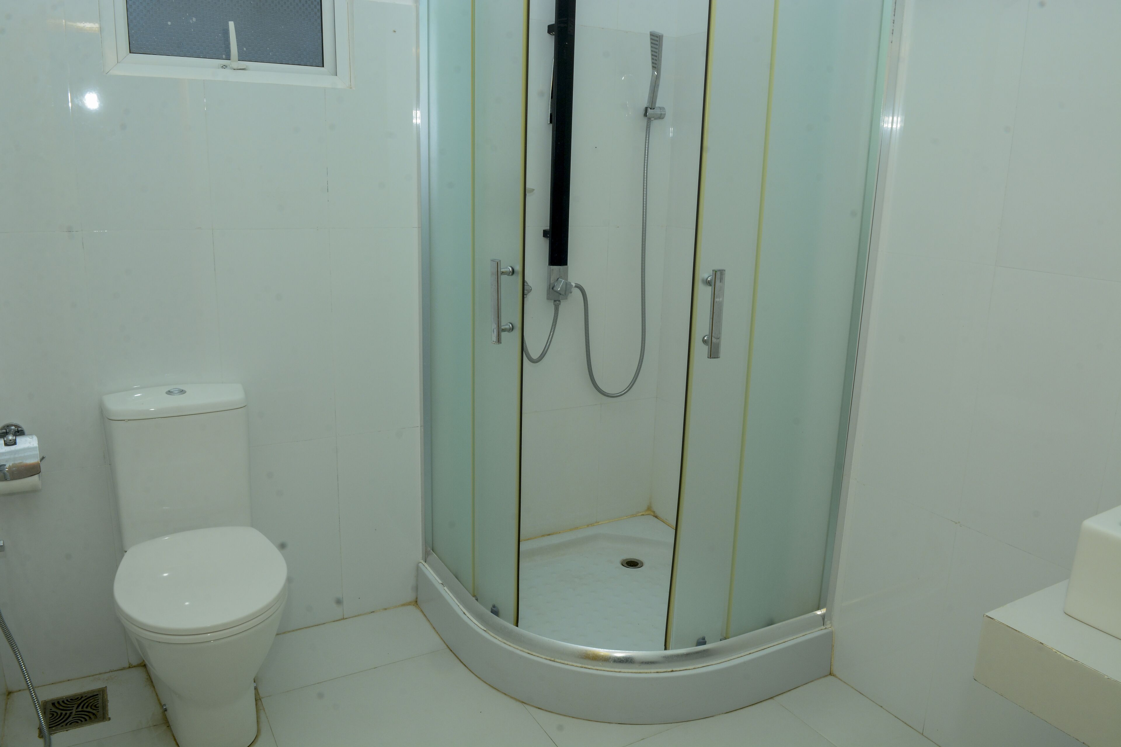 A bathroom with a toilet, a glass-enclosed shower, and a window.