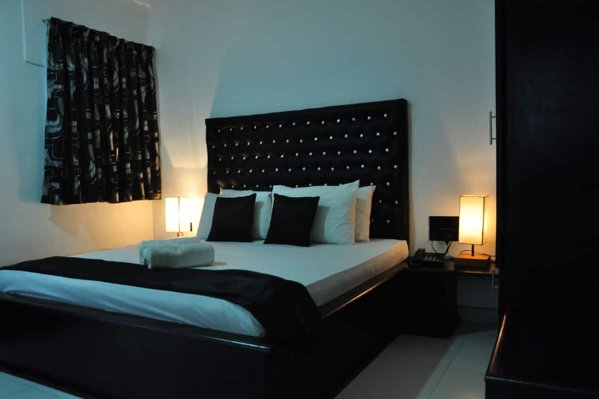 Ein Hotelzimmer mit einem großen Bett, zwei Nachttischen und einem gepolsterten Kopfteil.