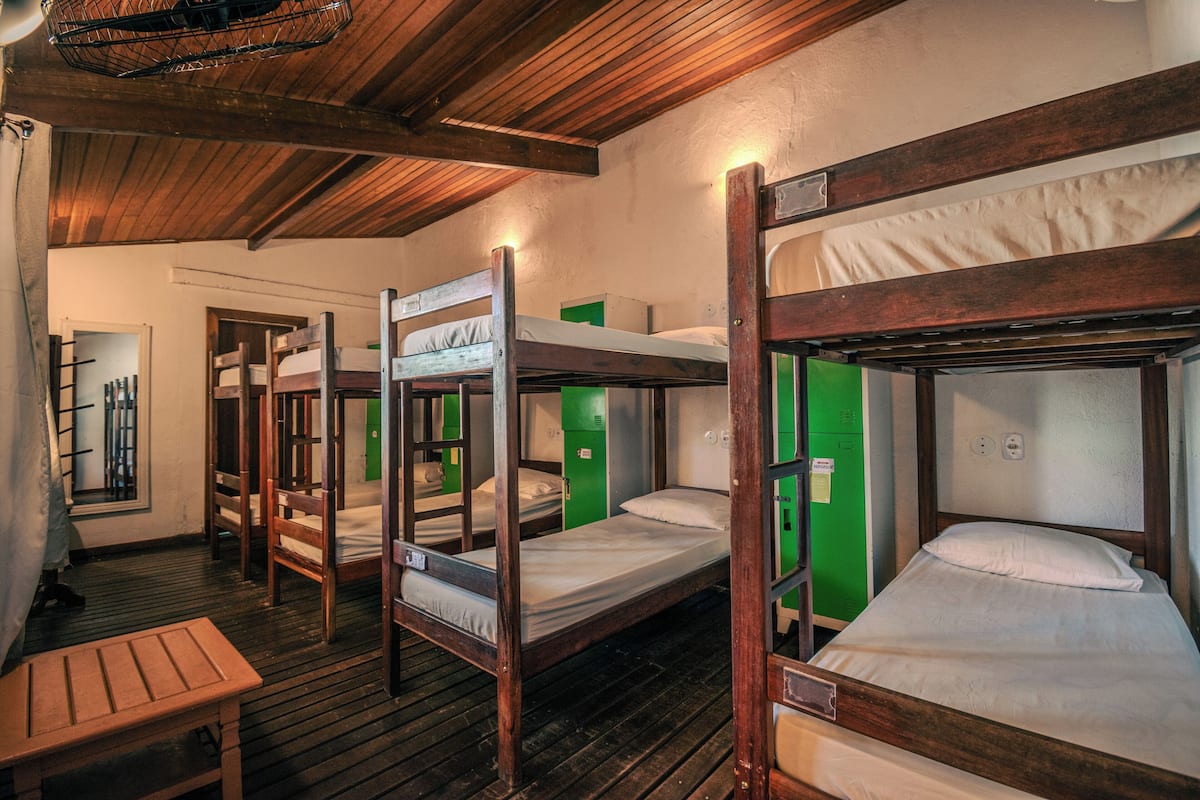 Un dormitorio con literas, muebles de madera y casilleros verdes.