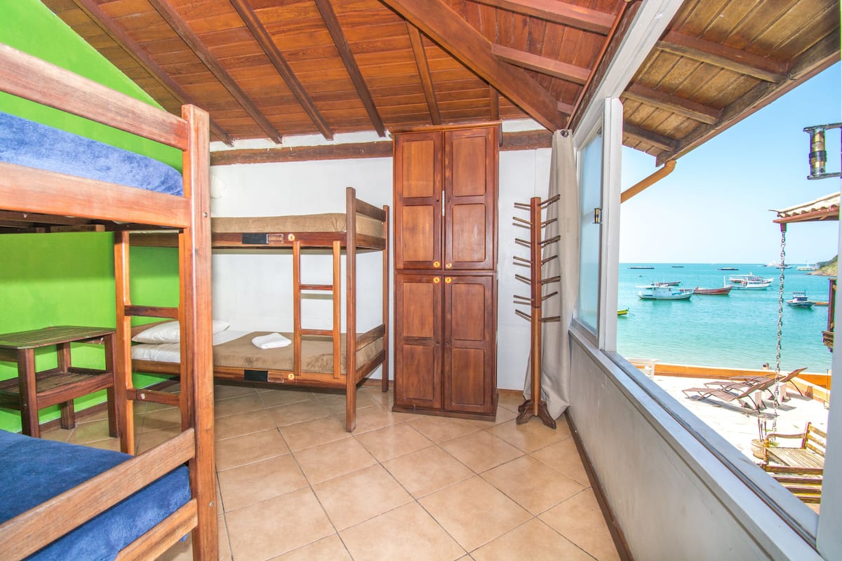 Un balcón con techo de madera, una cama litera, un armario y vistas a barcos en el agua.