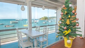 Een balkon met uitzicht op boten op het water, een kerstboom en witte meubels.