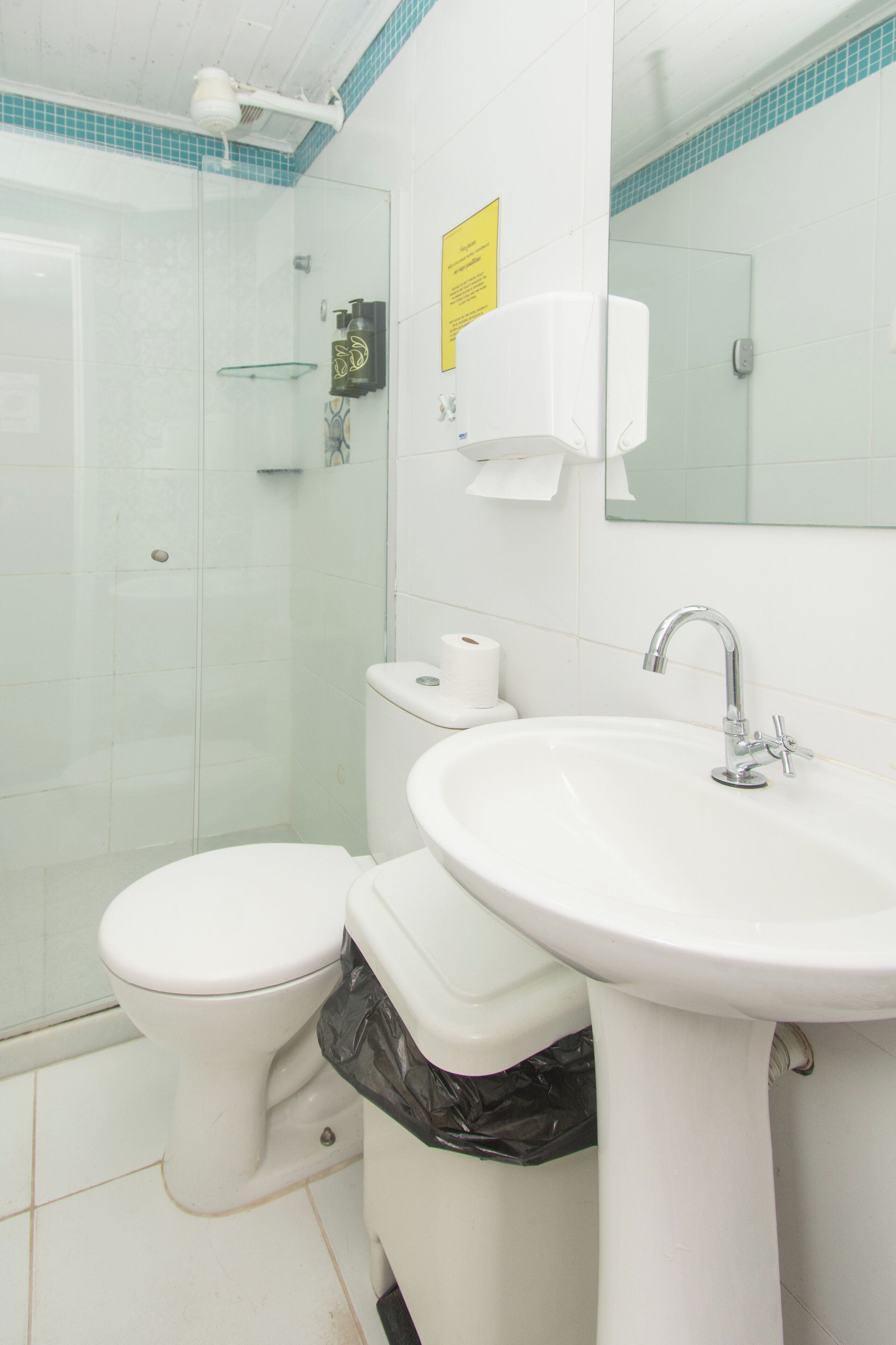 A bathroom with a toilet, sink, and glass shower enclosure.