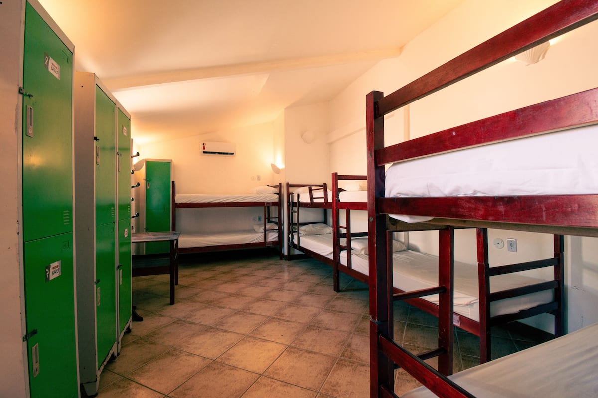 Un dormitorio con literas, taquillas verdes y una mesita.