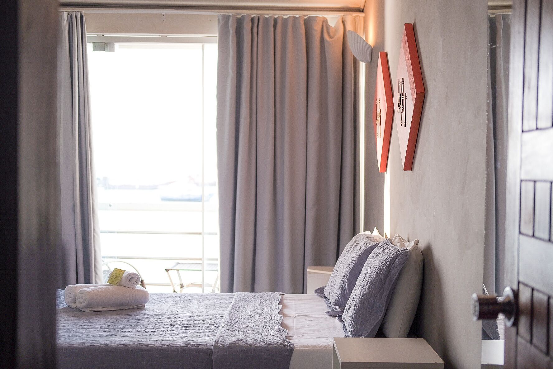 Quarto de hotel com cama, mesa de cabeceira e janela com cortinas.