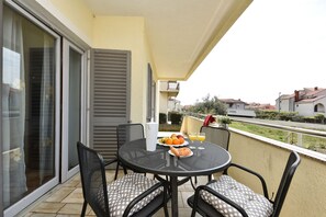 Un balcon avec une table ronde, des chaises et une assiette de fruits.