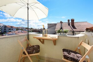 Un balcon avec deux chaises en bois, un parasol blanc et une bouteille de champagne.