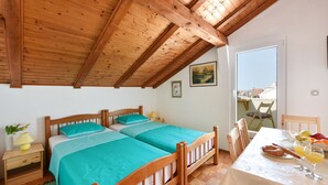 Una habitación con dos camas de madera, una mesa de comedor con alimentos para el desayuno y una ventana con vistas.
