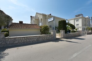 Un immeuble résidentiel avec un mur en pierre, une enseigne indiquant « Adria S » et un toit recouvert de tuiles.