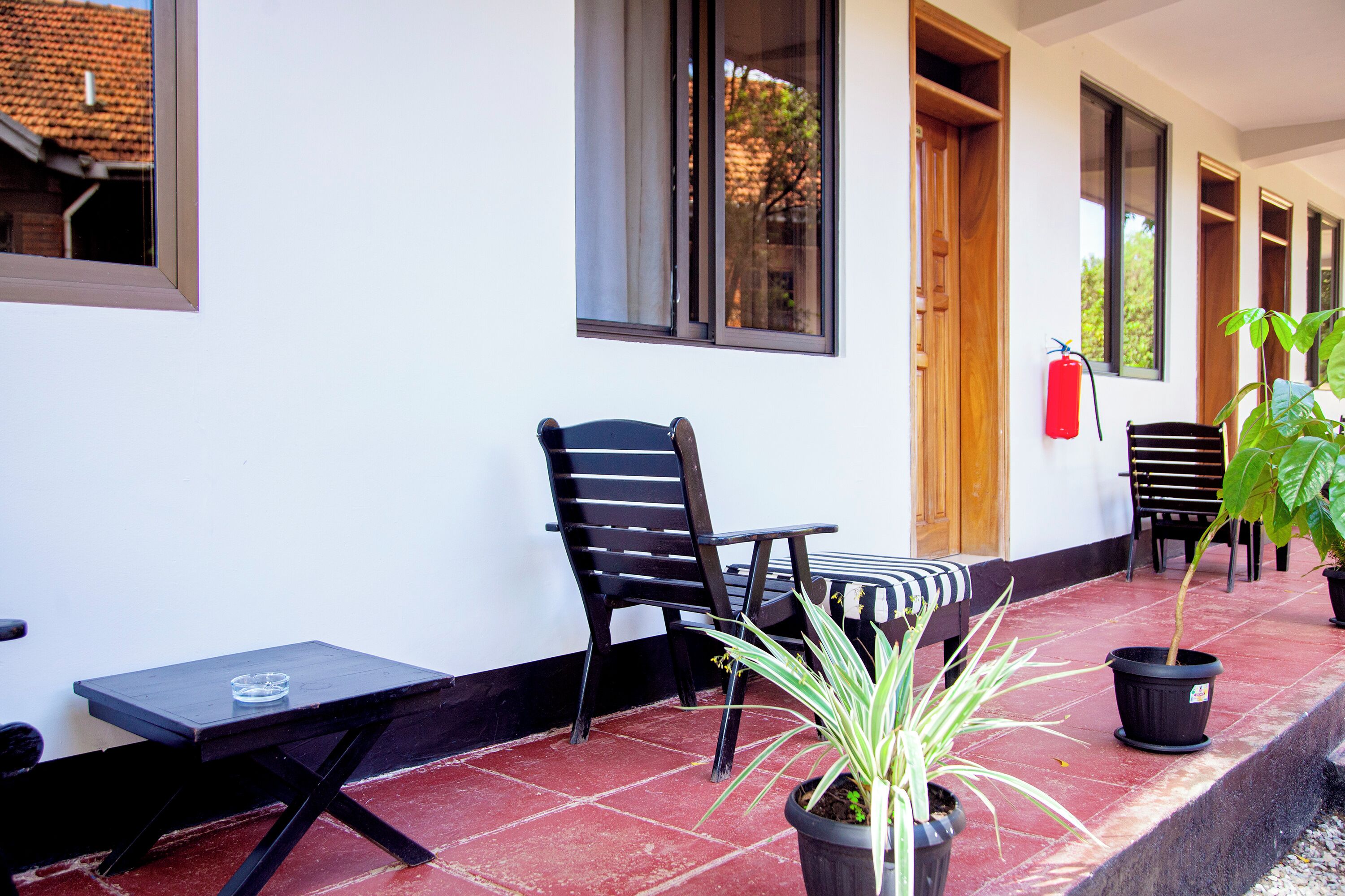 A covered outdoor seating area with a table, chairs, and potted plants.