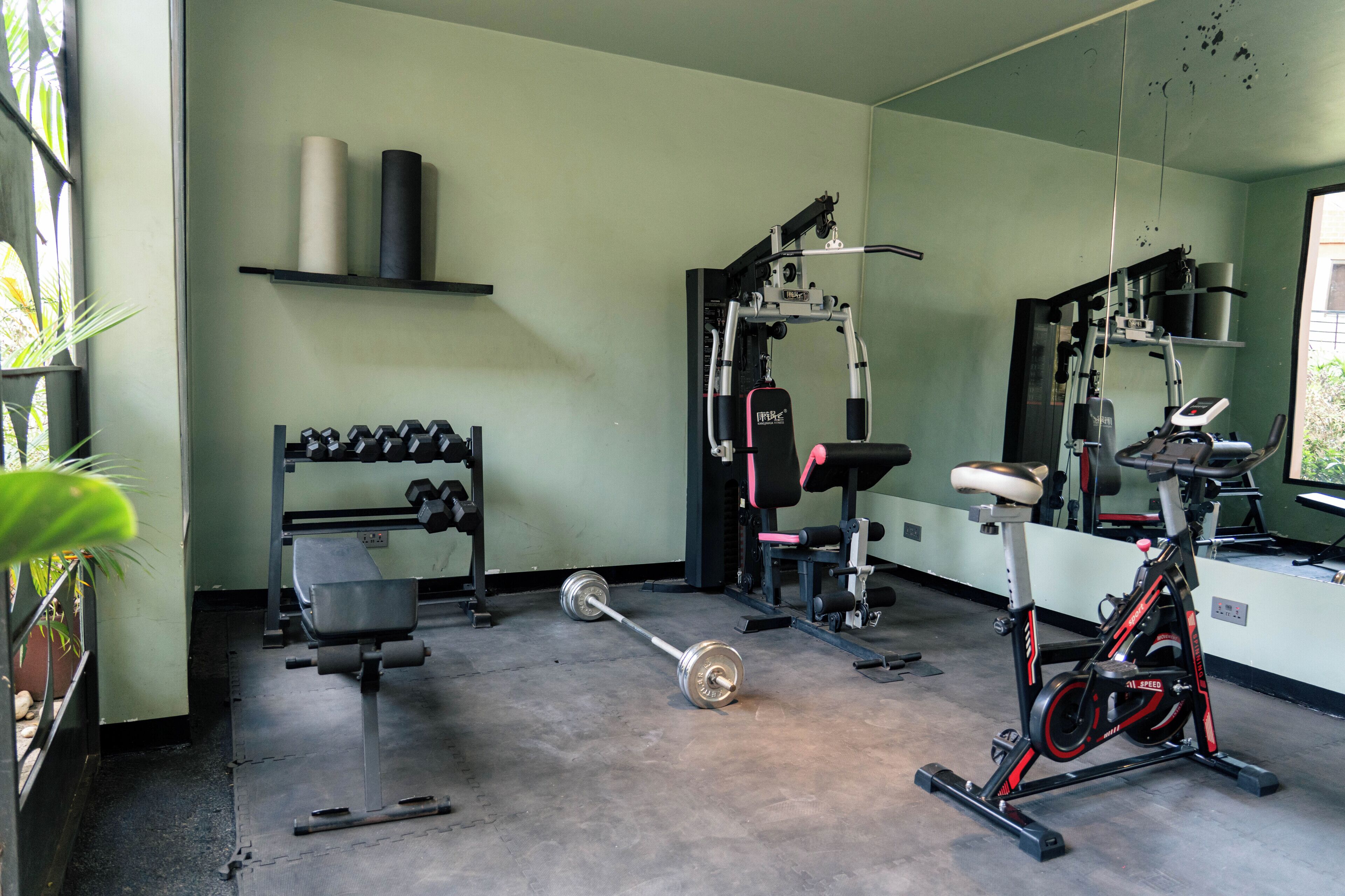 A gym with exercise equipment, a bench, and a bicycle.