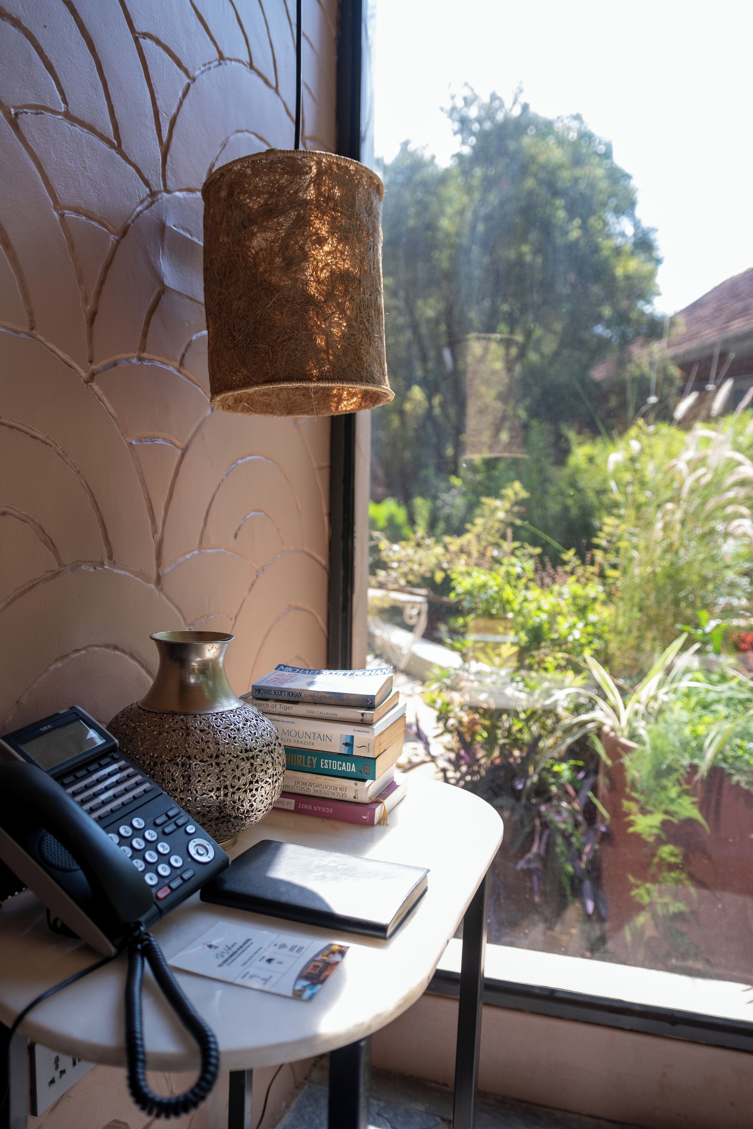 A desk with a telephone, a vase, and books.