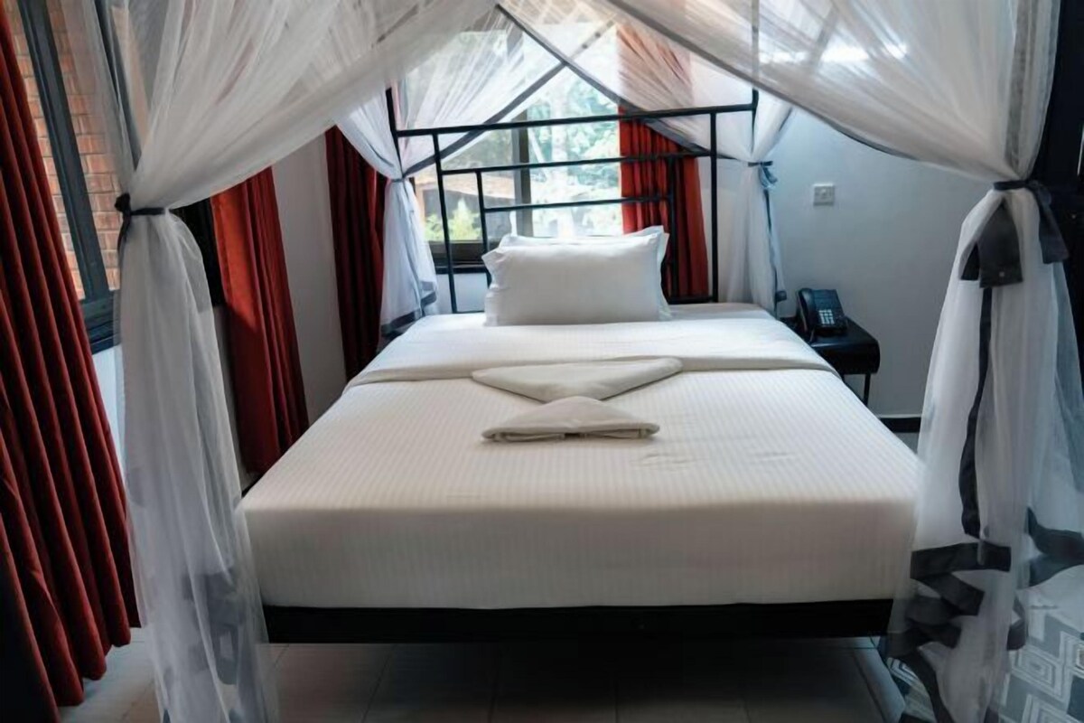 A bed with a canopy, a bedside table, and a phone on the wall.