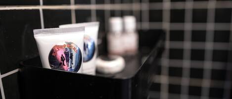 A black tray with a tube of cream and a bottle of lotion in a bathroom with black and white checkered tiles.