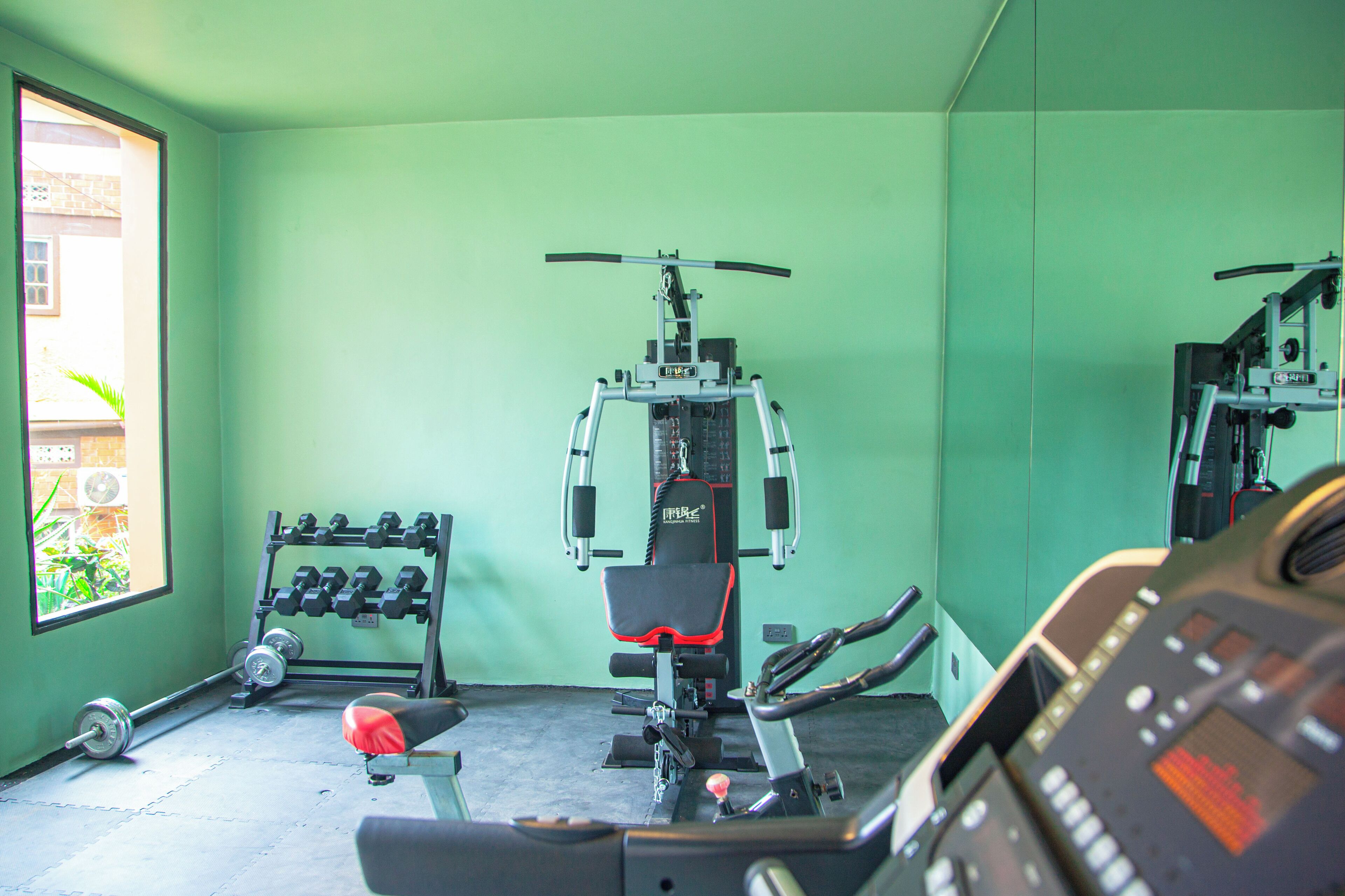 Une salle de sport équipée de machines d’exercice, d’un banc et d’haltères.